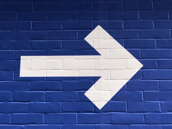 White arrow on blue brick background