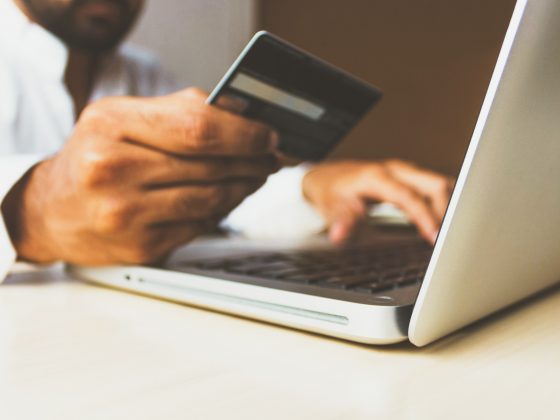 Close up of man's hand holding a credit card near his laptop