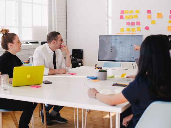 Office workers collaborating around a monitor