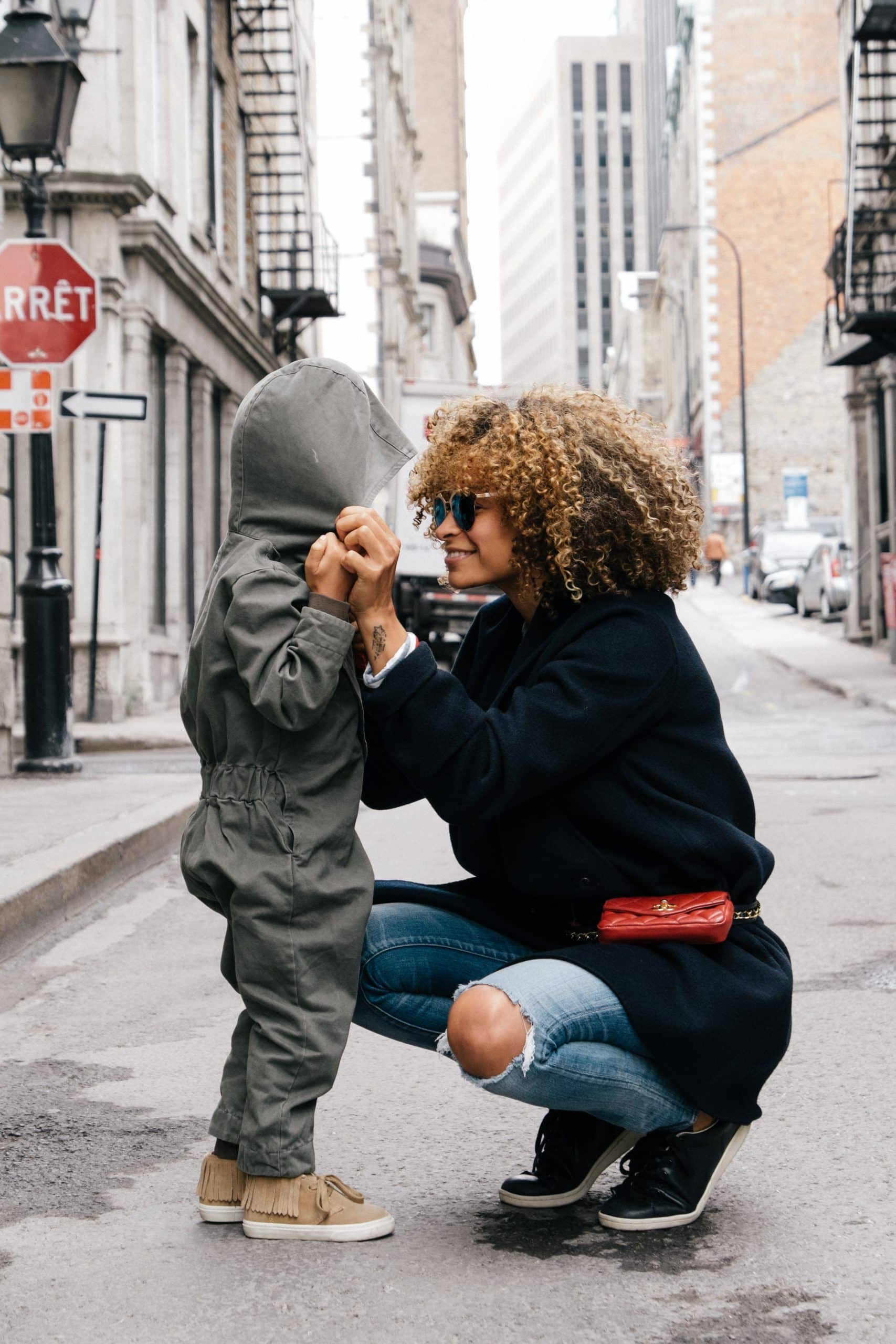 women crouching down to talk to kid on the street