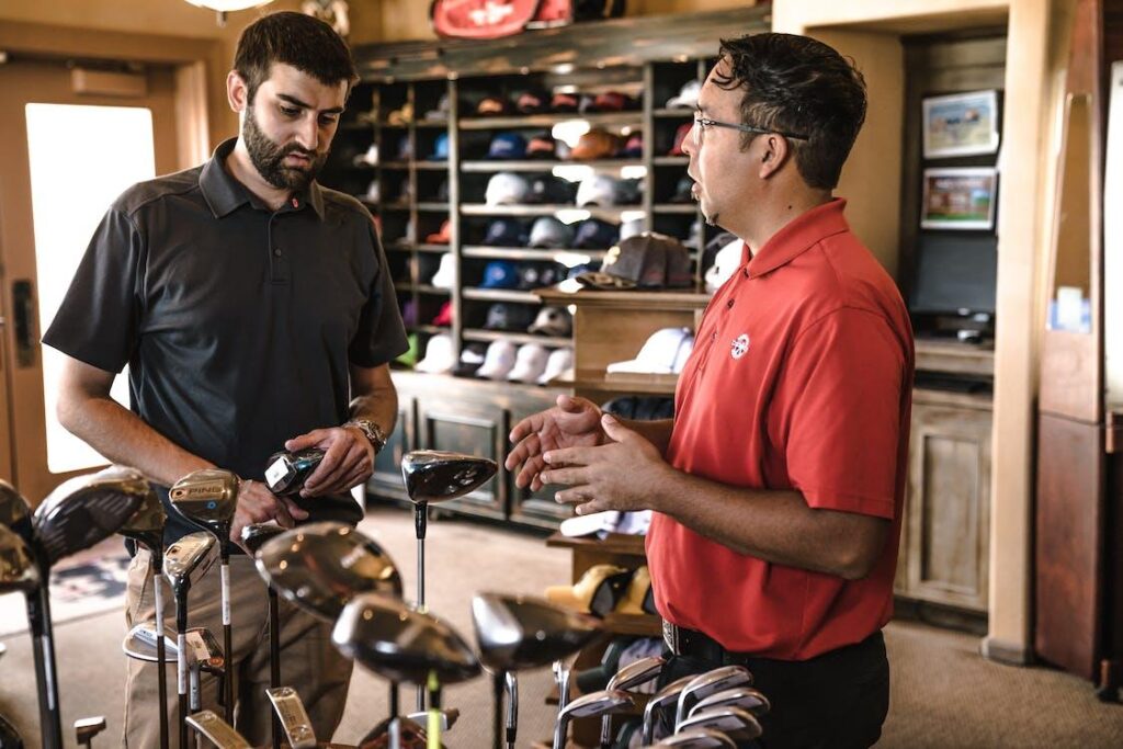 man standing beside man holding gray golf club